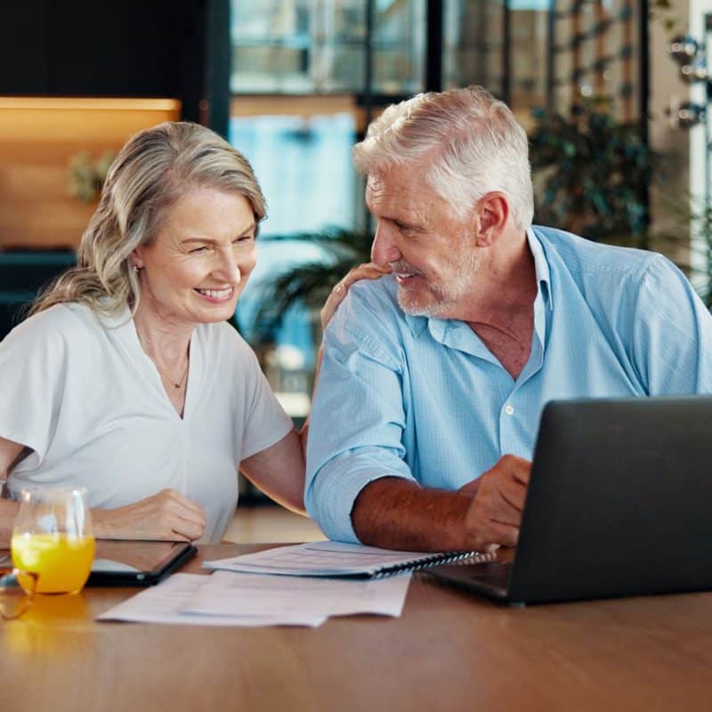 A man and a woman reviewing new 401(k) retirement contributions for 2026 from 401GO on a laptop.