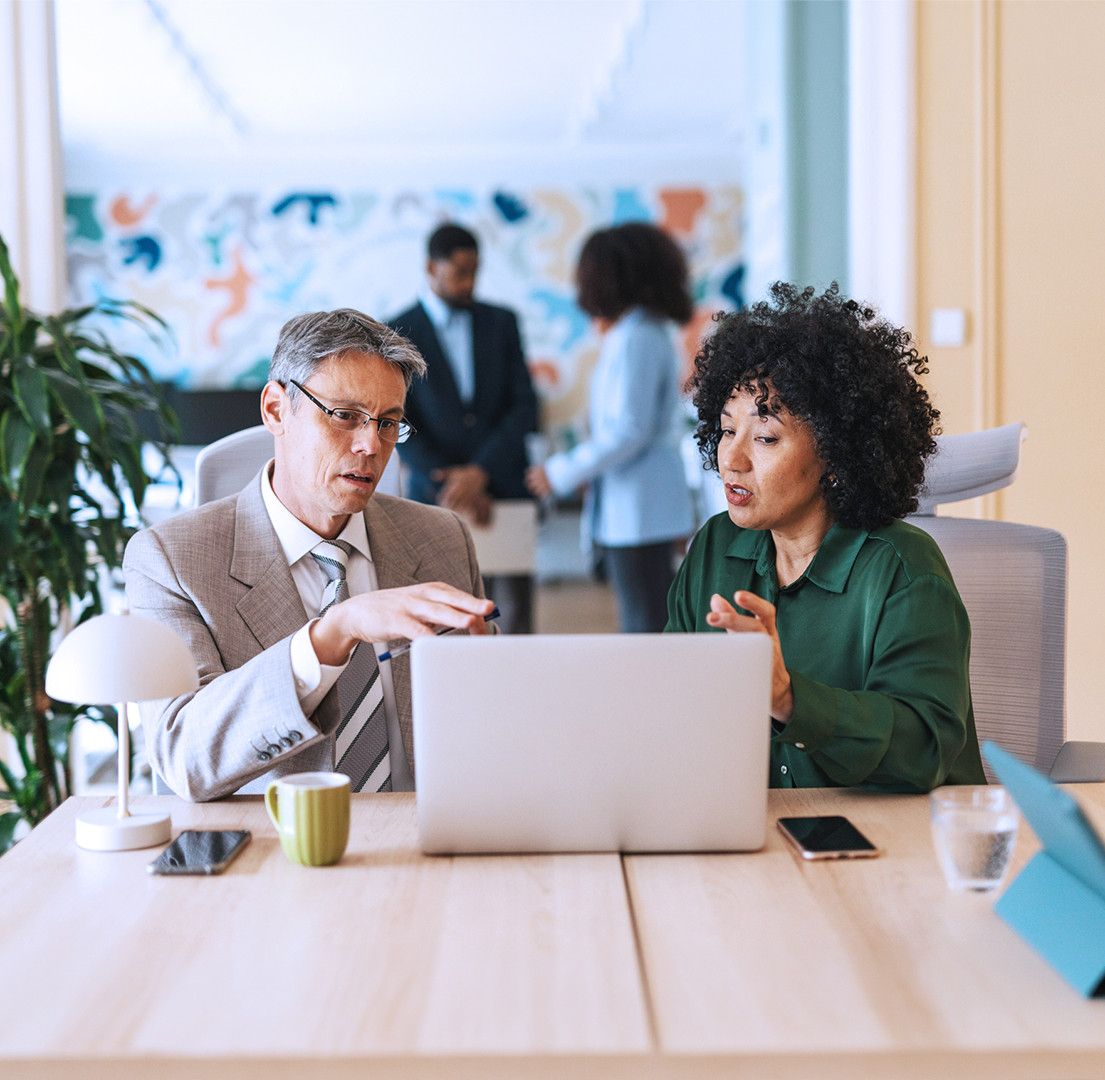 Financial professionals reviewing retirement plan information together on a laptop